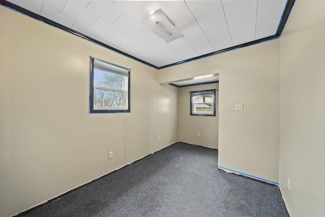 empty room with dark colored carpet and ornamental molding