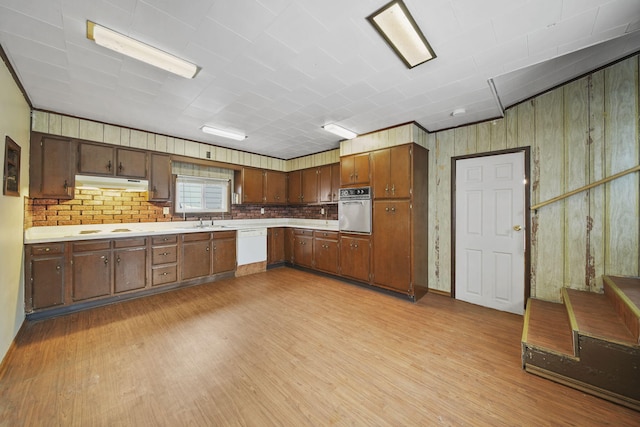 kitchen with light wood-type flooring, stainless steel oven, white dishwasher, sink, and stovetop