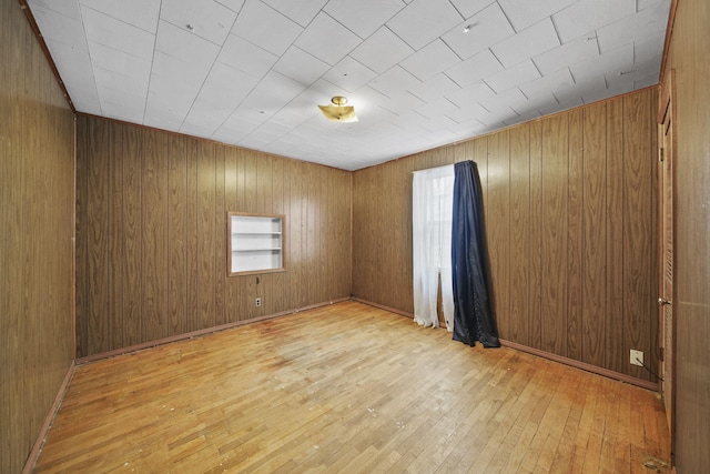 spare room featuring light hardwood / wood-style floors and wooden walls