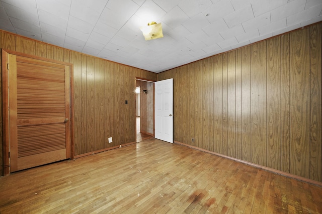 unfurnished bedroom featuring light wood-type flooring and wood walls