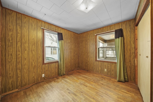 unfurnished room featuring wood walls and light hardwood / wood-style floors