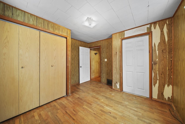 unfurnished bedroom featuring wood walls and light wood-type flooring