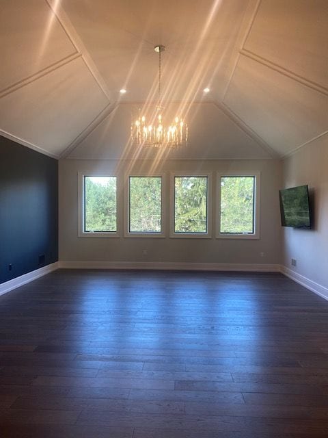 additional living space featuring vaulted ceiling, a healthy amount of sunlight, and an inviting chandelier