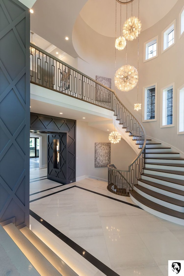 stairs featuring tile patterned floors, a towering ceiling, and an inviting chandelier