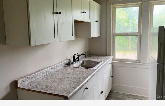 kitchen with white cabinetry, plenty of natural light, fridge, and sink