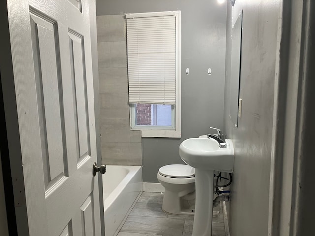 bathroom with a bathing tub, toilet, and sink