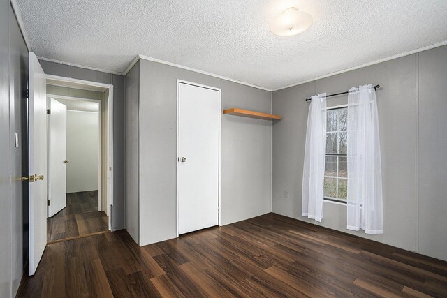 unfurnished bedroom featuring a textured ceiling, a closet, and dark wood-type flooring