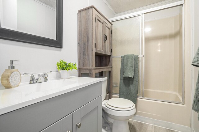 full bathroom featuring vanity, hardwood / wood-style flooring, toilet, enclosed tub / shower combo, and a textured ceiling