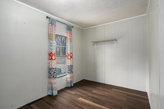 spare room with a textured ceiling, dark hardwood / wood-style floors, and ornamental molding