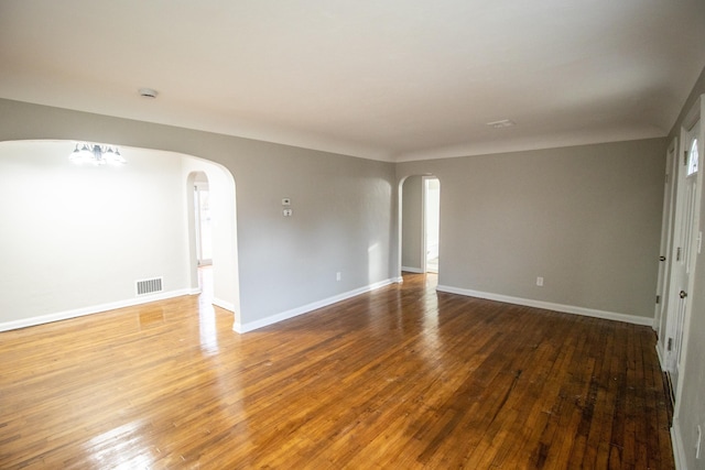 empty room with hardwood / wood-style floors and an inviting chandelier