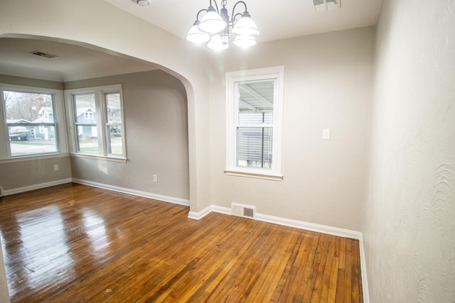 spare room featuring hardwood / wood-style floors and a chandelier