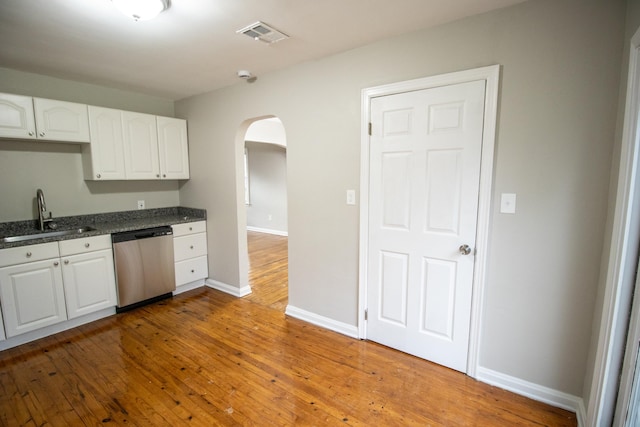 kitchen featuring stainless steel dishwasher, white cabinets, light wood-type flooring, and sink