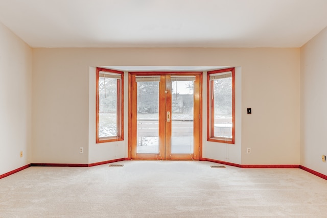 carpeted empty room featuring plenty of natural light and french doors