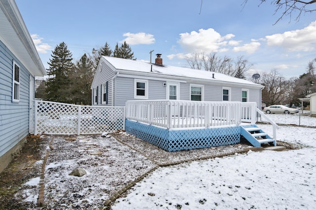 snow covered back of property with a wooden deck