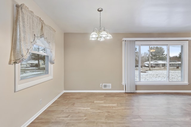 unfurnished dining area featuring light hardwood / wood-style floors and an inviting chandelier