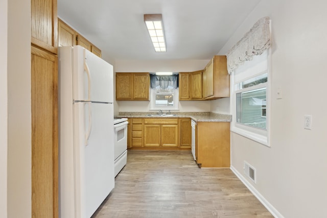 kitchen with light wood-type flooring, white appliances, and sink