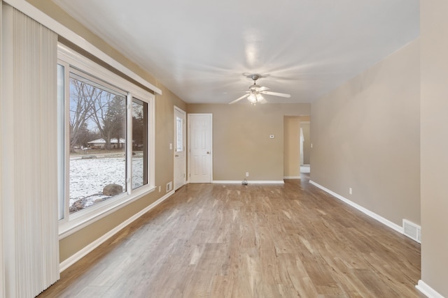 spare room featuring ceiling fan, light hardwood / wood-style floors, and a healthy amount of sunlight