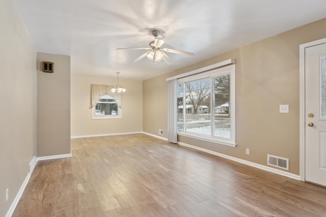 interior space with ceiling fan with notable chandelier and light hardwood / wood-style floors