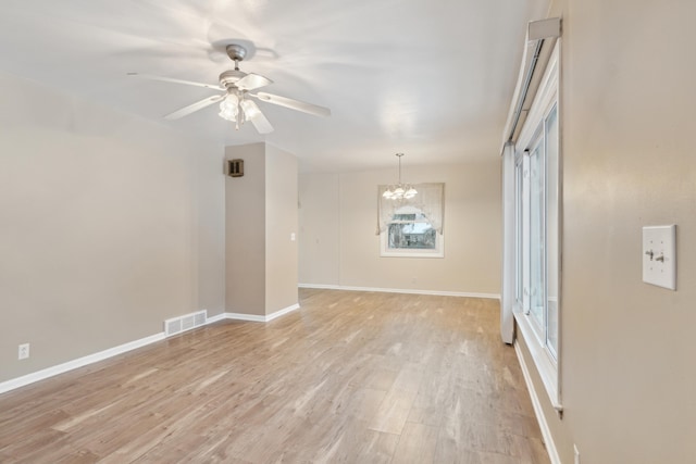 spare room featuring light hardwood / wood-style floors and ceiling fan with notable chandelier