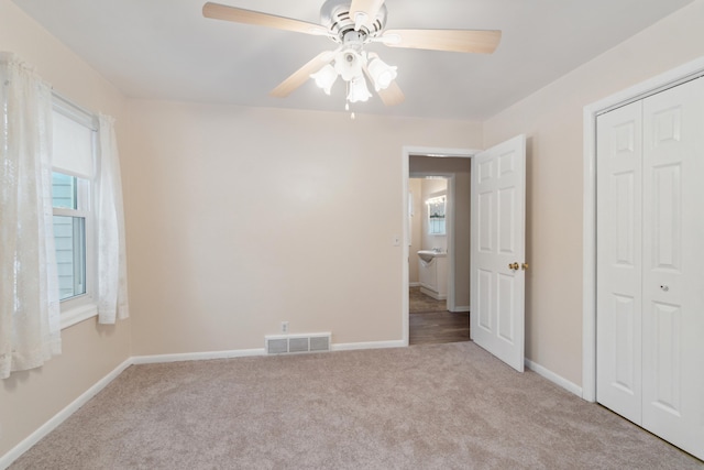 unfurnished bedroom with ceiling fan, light carpet, and a closet