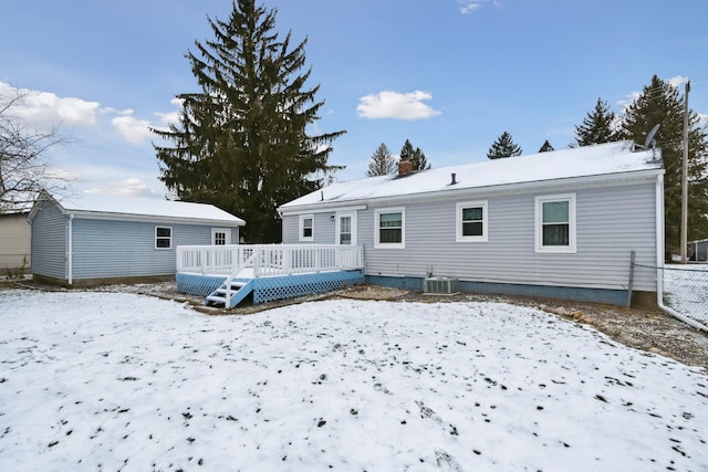 snow covered back of property with central AC and a deck