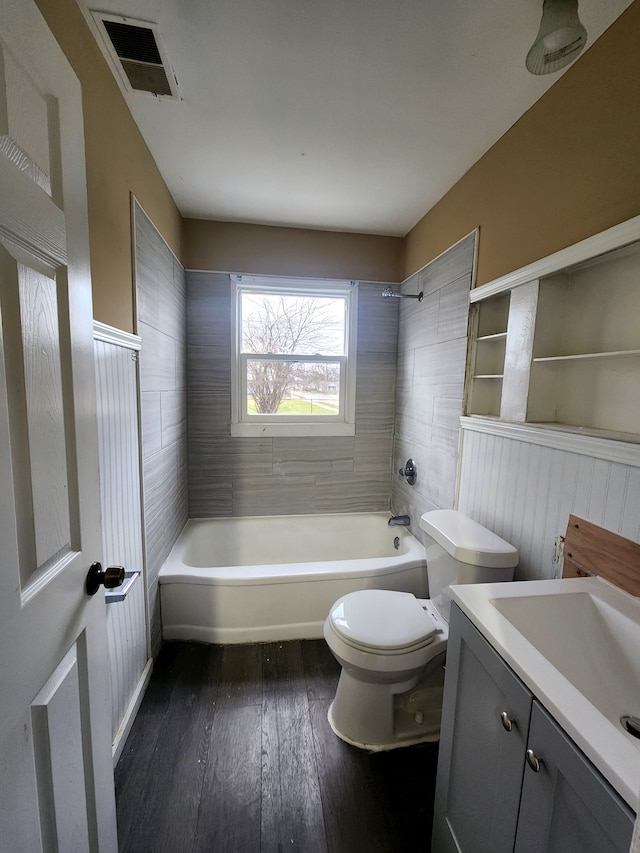 full bathroom with hardwood / wood-style flooring, vanity, tiled shower / bath combo, and toilet