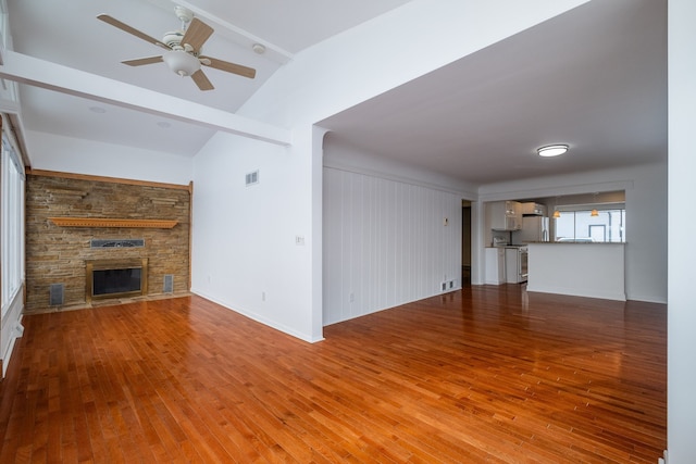 unfurnished living room with light hardwood / wood-style floors, vaulted ceiling with beams, ceiling fan, and a fireplace