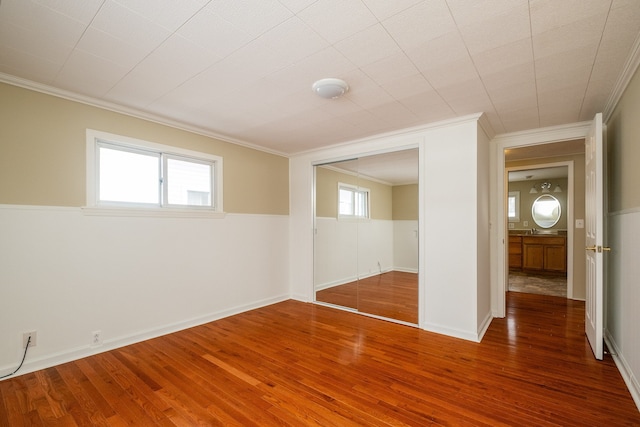 empty room with dark hardwood / wood-style flooring, a wealth of natural light, and ornamental molding