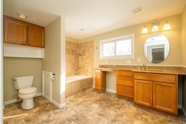 bathroom featuring tiled tub, toilet, and vanity