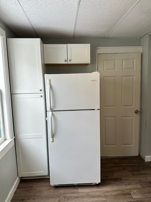 kitchen with a paneled ceiling, white refrigerator, dark hardwood / wood-style flooring, and white cabinetry