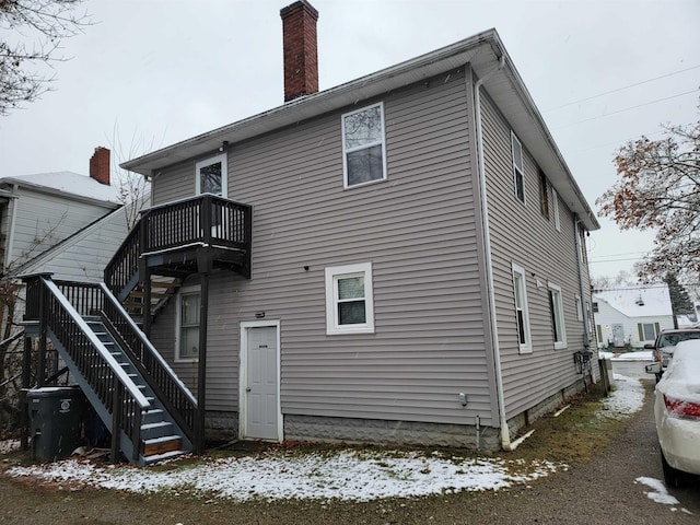 snow covered back of property with a balcony