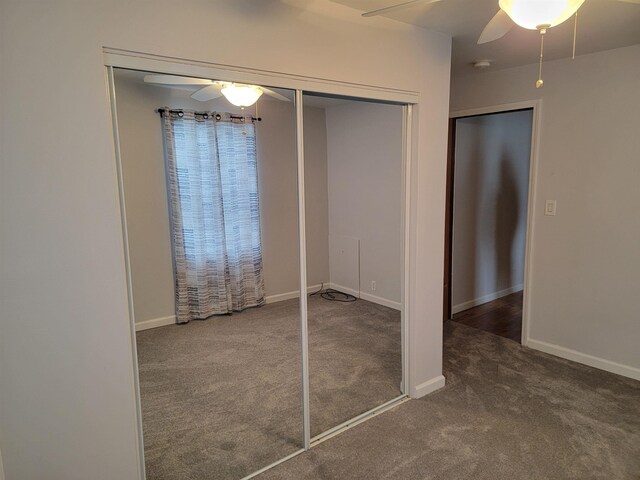 unfurnished bedroom featuring a closet, dark carpet, and ceiling fan