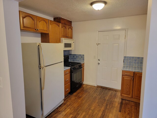 kitchen with a textured ceiling, white appliances, dark wood-type flooring, and tasteful backsplash