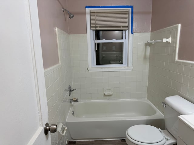 full bathroom with tile walls, vanity, tiled shower / bath combo, and toilet