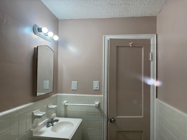 bathroom with tile walls, vanity, and a textured ceiling