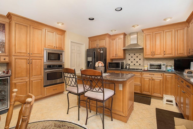 kitchen with a breakfast bar, a center island, wall chimney exhaust hood, appliances with stainless steel finishes, and tasteful backsplash