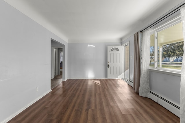 unfurnished room featuring dark hardwood / wood-style floors and a baseboard heating unit