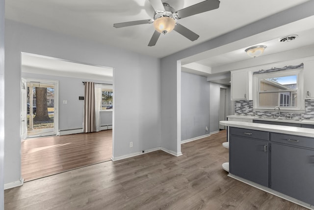 kitchen featuring tasteful backsplash, a baseboard heating unit, wood-type flooring, gray cabinets, and white cabinetry