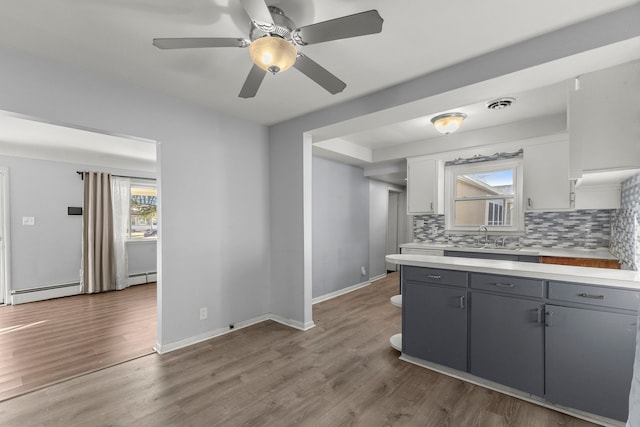 kitchen featuring gray cabinetry, tasteful backsplash, a baseboard radiator, white cabinetry, and wood-type flooring