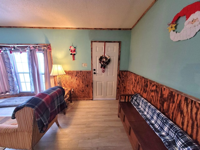 bedroom with a textured ceiling, light hardwood / wood-style floors, and ornamental molding