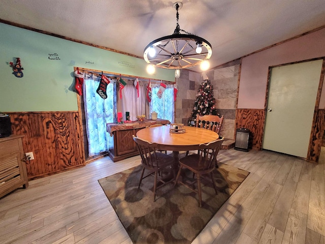 dining area featuring crown molding, light wood-type flooring, a textured ceiling, and an inviting chandelier