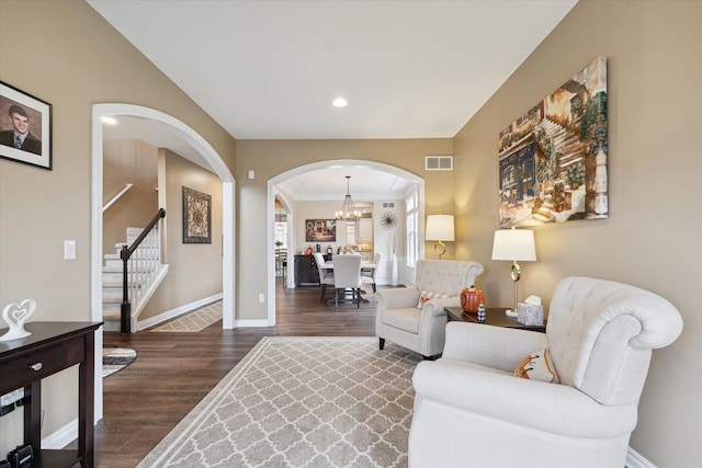 living room featuring a chandelier, dark hardwood / wood-style flooring, and ornamental molding