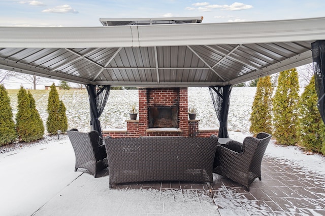 snow covered patio featuring a gazebo and an outdoor brick fireplace