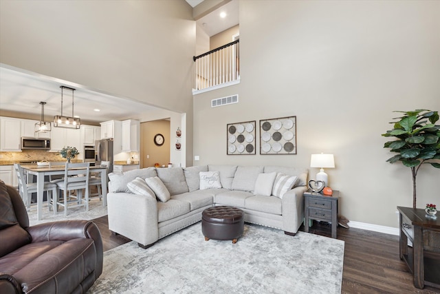 living room featuring a towering ceiling and dark wood-type flooring