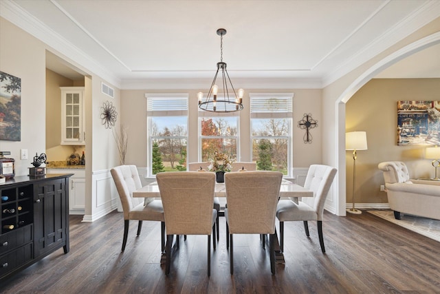 dining space with an inviting chandelier, crown molding, and dark wood-type flooring