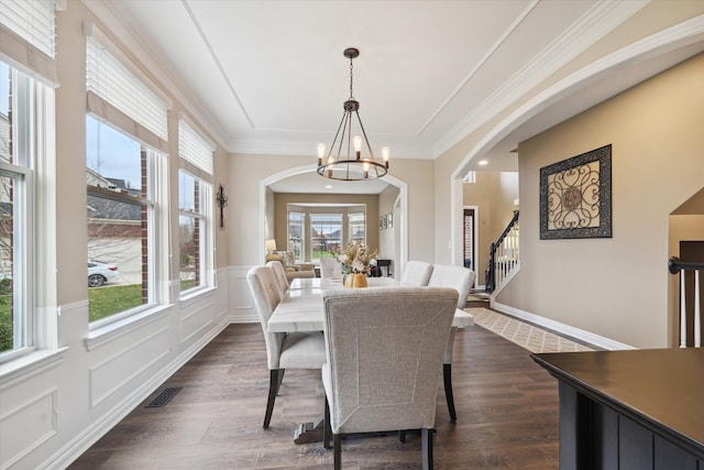 dining space with dark hardwood / wood-style flooring, ornamental molding, a wealth of natural light, and an inviting chandelier