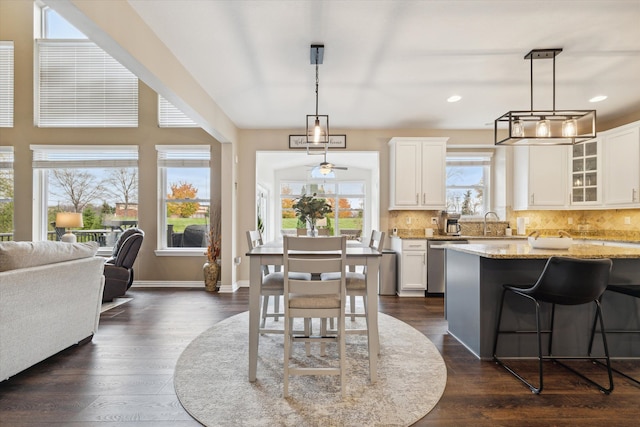 kitchen featuring stainless steel dishwasher, decorative light fixtures, light stone countertops, and white cabinetry