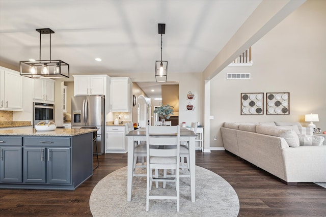 kitchen featuring hanging light fixtures, stainless steel appliances, light stone counters, backsplash, and white cabinets