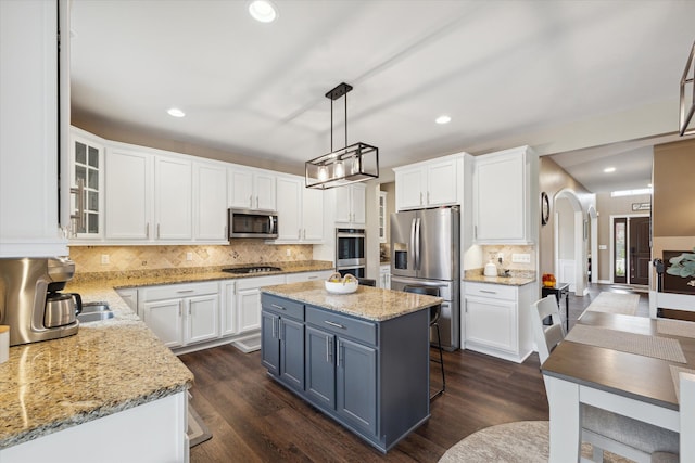 kitchen featuring white cabinets, appliances with stainless steel finishes, a kitchen island, and hanging light fixtures