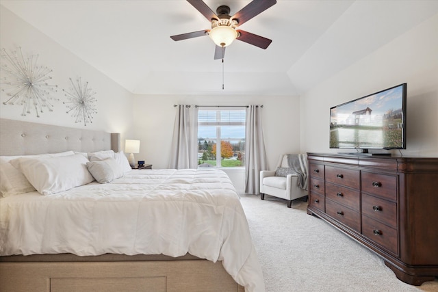 bedroom with light carpet, a tray ceiling, vaulted ceiling, and ceiling fan